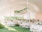 Configuración interior de recepción con mesas blancas y decoración floral bajo carpa