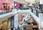 Interior del centro comercial con múltiples niveles, tiendas y pasillos iluminados
