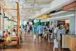 Interior del food hall de Optimist Park con puestos de comida y comensales sentados
