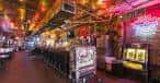 Barra larga con luces de neón y máquinas tragamonedas