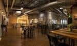 Espacio interior industrial con mesas altas y tuberías expuestas