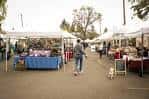 Vista general del mercado con puestos bajo carpas blancas y personas caminando