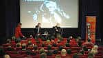 Evento en el interior del teatro con audiencia y panelistas frente a pantalla