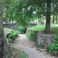 Sendero peatonal bordeado por muros de piedra y vegetación en el parque