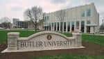 Entrada principal de Butler University con letrero de piedra y edificio moderno al fondo