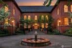 Patio interior iluminado por la noche con fuente central y fachada de ladrillo del edificio escolar