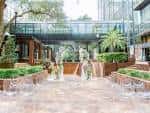Área de ceremonia al aire libre con arcos decorativos y sillas blancas