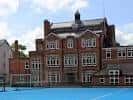 Vista exterior del edificio principal de Nottingham Girls' High School GDST con fachada de ladrillo rojo y patio azul