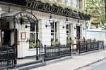 Fachada exterior del The Mad Hatter Hotel con detalles victorianos y toldo