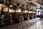 Interior del pub con paneles de madera, mesas individuales y suelo a cuadros
