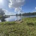 Paisaje natural del parque con césped, agua y cielo azul con nubes