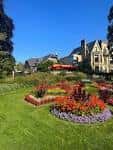 Jardines ornamentales con diseños florales coloridos y edificios históricos al fondo