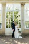 Pareja de novios posando frente a una gran ventana de cristal dentro del jardín botánico