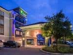 Fachada nocturna del hotel con iluminación ambiental y vehículos en estacionamiento