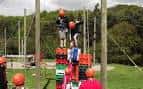 Actividad de escalada en altura con participantes usando cascos naranjas
