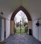Vista desde el interior de la entrada arqueada hacia los jardines del cementerio