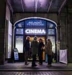 Entrada nocturna del Belmont Filmhouse con personas frente a la puerta iluminada