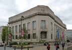 Fachada principal de la biblioteca con banderines decorativos y peatones en primer plano