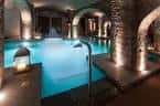 Piscina interior iluminada con arcos de piedra y ambiente relajante
