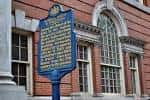 Placa histórica azul frente a la fachada de ladrillo del edificio