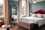 Habitación doble decorada con tonos azules, cabecero rojo y vistas a la ciudad