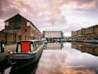 Canal con embarcación y almacenes históricos al atardecer