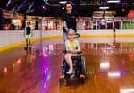 Persona en silla de ruedas patinando en pista de roller rink con luces de neón