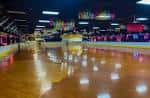 Pista de patinaje vacía con iluminación colorida y reflejos en el suelo