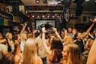 Interior animado del pub con clientes celebrando y levantando las manos