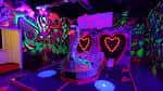 Área interior con iluminación UV, corazones luminosos y arte callejero