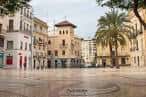 Plaza vacía con pavimento decorativo y edificios coloniales alrededor, incluyendo una torre central