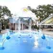 Zona de juego acuático con fuentes y estructuras de sombra en el parque