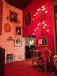Sala de entrada con paredes rojas, cuadros decorativos y mobiliario vintage característico del restaurante