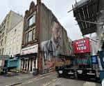Fachada exterior del Ulster Sports Club en Belfast con murales artísticos y letrero rojo