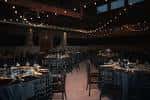 Salón de eventos decorado con mesas redondas y luces colgantes