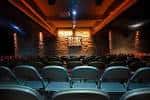 Interior del auditorio de Monkey Barrel Comedy con butacas y escenario iluminado