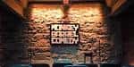 Pared de piedra con el logotipo iluminado de Monkey Barrel Comedy
