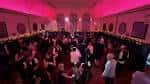 Interior del salón principal con iluminación rosa y asistentes celebrando