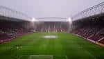 Vista interior del estadio Tynecastle Park con gradas y campo de fútbol iluminado