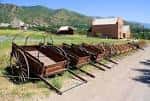 Carretas de madera tradicionales alineadas en un camino rural con graneros al fondo