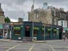 Vista exterior de Dougal's Pub en una esquina de Edimburgo con fachada verde y detalles arquitectónicos históricos