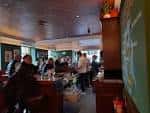 Interior acogedor del pub con clientes sentados en mesas, iluminación cálida y decoración tradicional escocesa