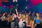 Interior del club con gente bailando bajo luces de neón