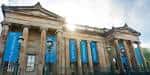 Entrada frontal del Scottish National Gallery con banderines azules y sol brillante