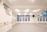 Interior luminoso del estudio de danza con ventanas grandes y suelo de madera