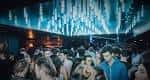 Interior del club con iluminación azul y multitud de personas disfrutando la noche