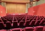 Interior del auditorio con butacas rojas y cortina dorada