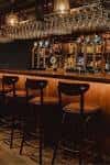 Interior del bar con estantería de copas y taburetes