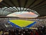Vista panorámica del interior del estadio durante un partido con gradas llenas y campo de juego iluminado