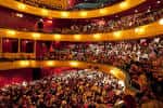 Interior del auditorio con butacas rojas y público durante una función